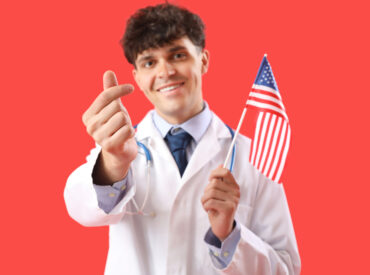 Male doctor with USA flag making heart shape on red background, closeup